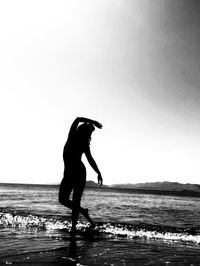 Full length of silhouette woman standing on beach against clear sky