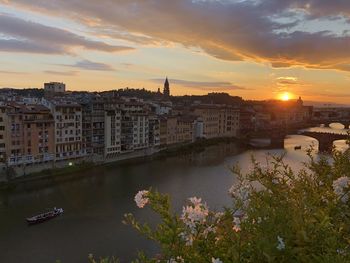 River amidst buildings against sky during sunset