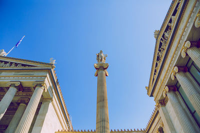 Low angle view of statue against building against clear blue sky