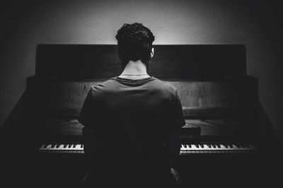 Rear view of man playing piano