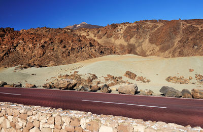 Road by rock formations against blue sky at teide national park