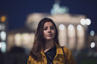 Portrait of woman standing in city at night