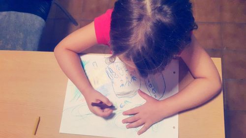 High angle view of girl drawing on paper at table