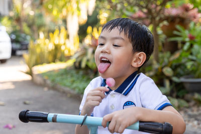 Cute boy eating lollipop while on footpath