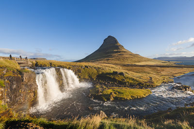 Scenic view of waterfall against clear blue sky