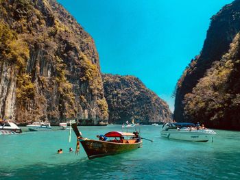 Boats in sea against clear blue sky