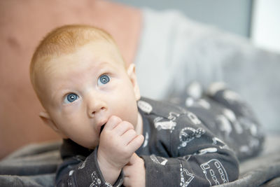 Close-up of adorable newborn baby boy sucking his hand or finger thumb