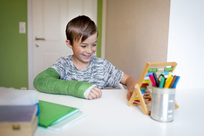 Portrait of smiling boy sitting on table at home