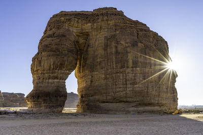 Rock formations on beach against clear sky