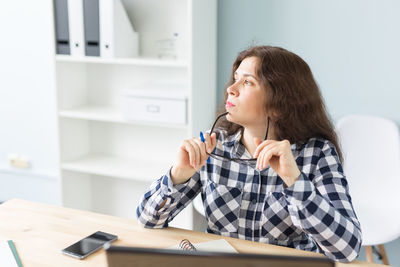 Young woman looking down while sitting on table