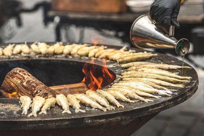 Preparing traditional tasty fried european smelt fish cooked on an open fire in a street food market