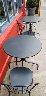 Empty chairs and tables at sidewalk cafe