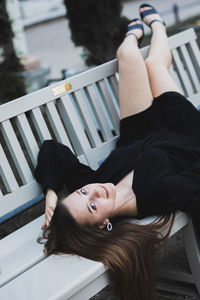 Portrait of young woman lying down on railing