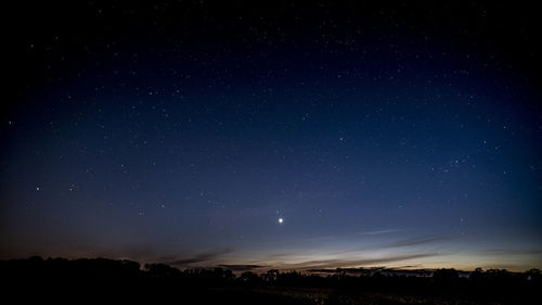 Silhouette landscape against star field at night