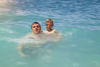 Portrait of boy with father swimming in sea