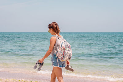 Rear view of man standing at beach against sky