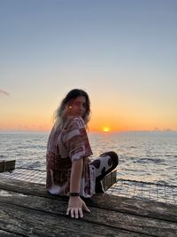 Rear view of woman standing on beach against sky during sunset