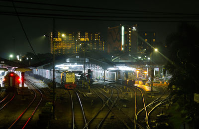 Illuminated railroad tracks in city at night
