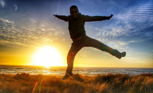 Silhouette man at beach against sky during sunset
