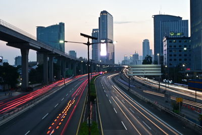 Light trails on highway in city against sky