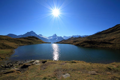 Scenic view of lake and mountains against blue sky