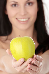 Close-up portrait of a young woman holding apple