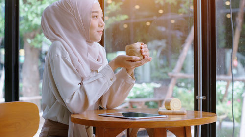 Smiling woman in hijab sitting at cafe