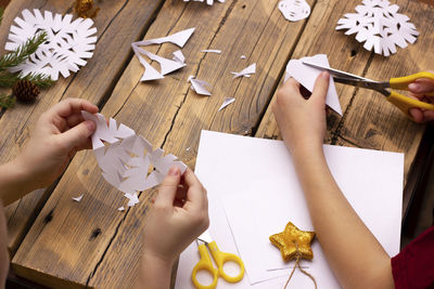 Cropped hands of woman holding christmas decorations on table