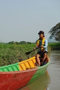 Man sitting in boat against clear sky