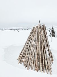 Wooden posts on snow covered land against sky