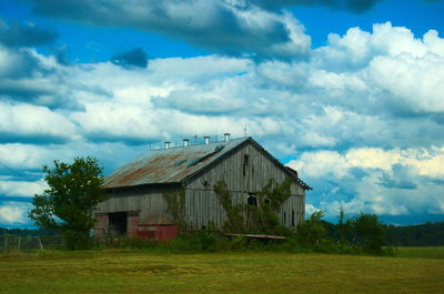 Houses on field against cloudy sky