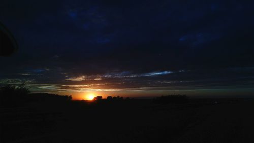 Scenic view of silhouette field against sky at sunset