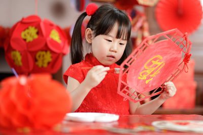 Young chinese girl making traditional chinese gretting card for celerating chinese new year