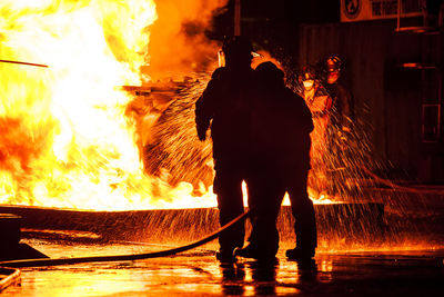 Rear view of man working on fire at night