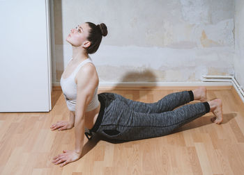 Side view of young woman lying on hardwood floor at home