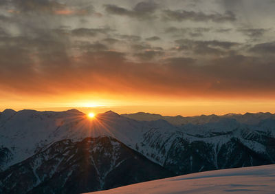 Scenic view of snowcapped mountains against sky during sunset