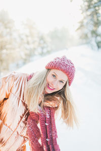 Portrait of smiling young woman standing against snow