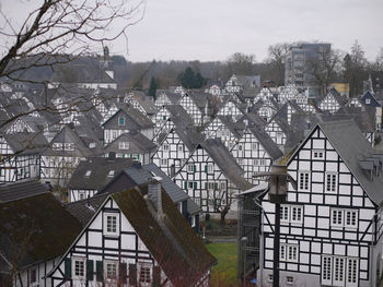 Houses and trees in city against sky during winter