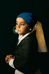 Portrait of young man standing against black background