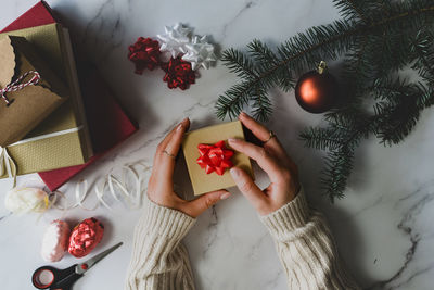 Directly above shot of woman holding gift box on table