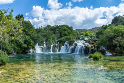 View of waterfall against cloudy sky