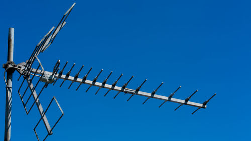 Low angle view of antenna tv against clear blue sky