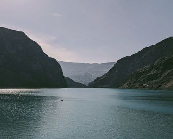 Scenic view of sea by mountains against sky