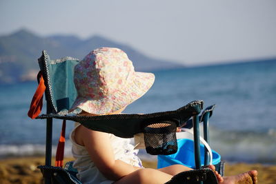 Rear view of woman wearing hat standing at beach