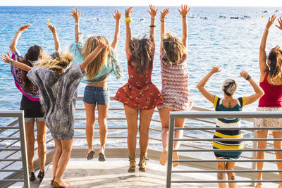 Rear view of friends jumping on pier at beach