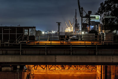 Industrial buildings against cloudy sky at night