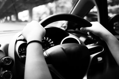 Cropped hands holding steering wheel of car