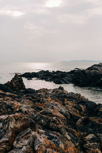 Rock formation on beach against sky