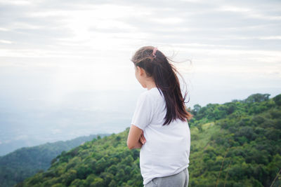 Young woman looking at waterfall against sky
