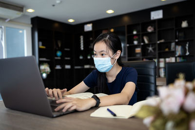 Woman using phone while sitting on table